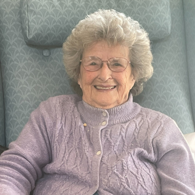 Female smiling at the camera, sitting in a blue chair