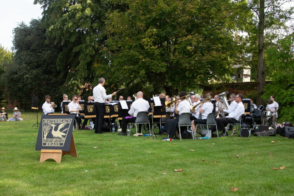 Men and women with Brass instruments playing in a green area