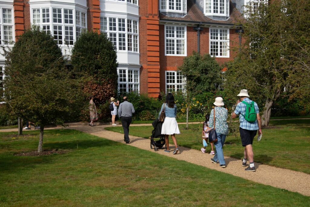 People walking to a large building along a garden path 