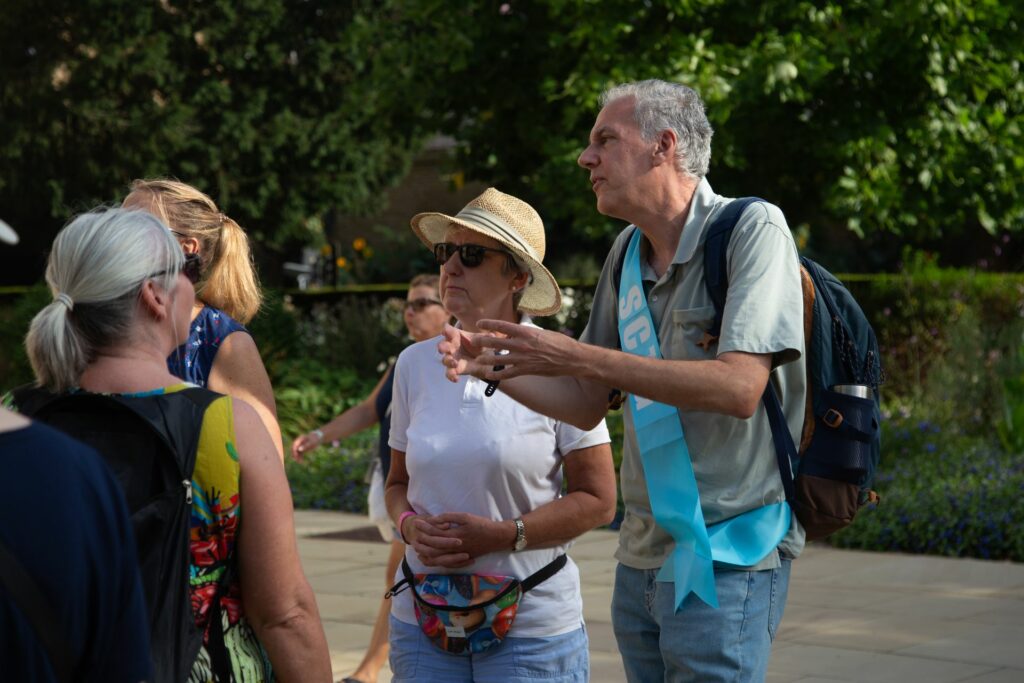 Females listening to a male wearing a blue tour guide sash