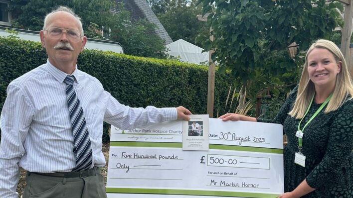 Male and female in the garden holding a large cheque
