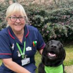 Female nurse and black dog smiling at the camera