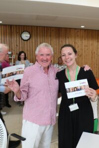 Male and female holding a booklet and smiling at the camera 