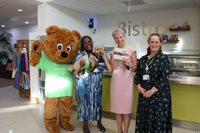 Life sized bear, and 3 females standing at a Bistro counter