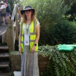 Female wearing a sunhat and high vis waistcoat, standing in a garden