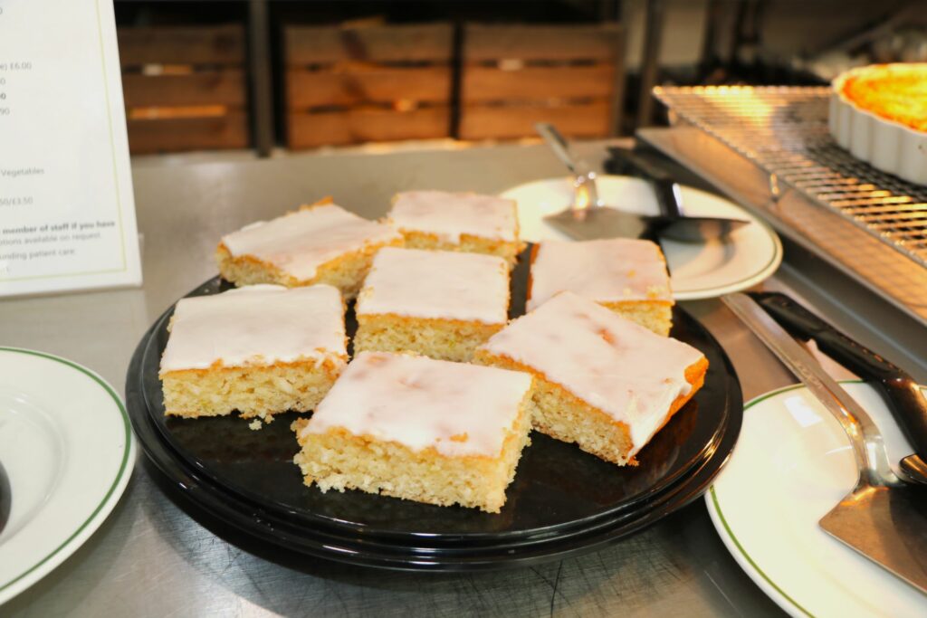 Slices of blonde cake with white icing on a black plate