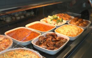 display of food. red spicy rice, jerk chicken, macaroni and cheese, steamed vegetables