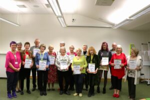 Group of people holding their certificates and smiling at camera