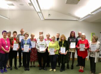 Group of people holding their certificates and smiling at camera