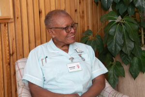 Female nurse wearing glasses sitting on a chair smiling 