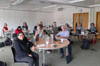 Group of males and females sitting at tables smiling at the camera