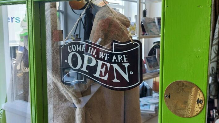 Green door and a chalk board type sign that says "come in, we are open"