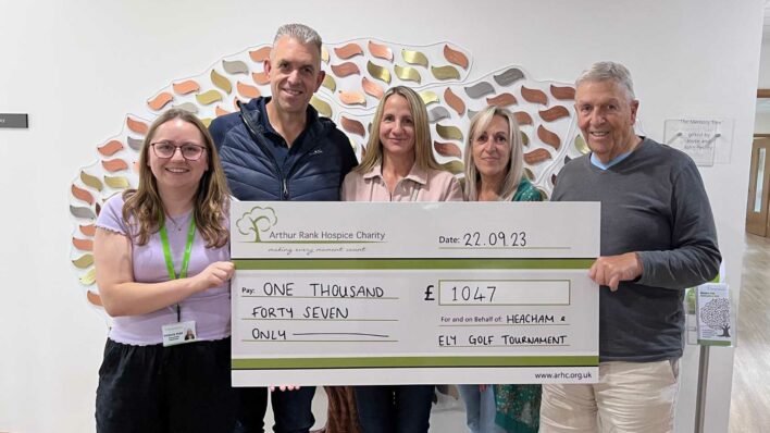 Image five people holding large cheque in front of memory tree