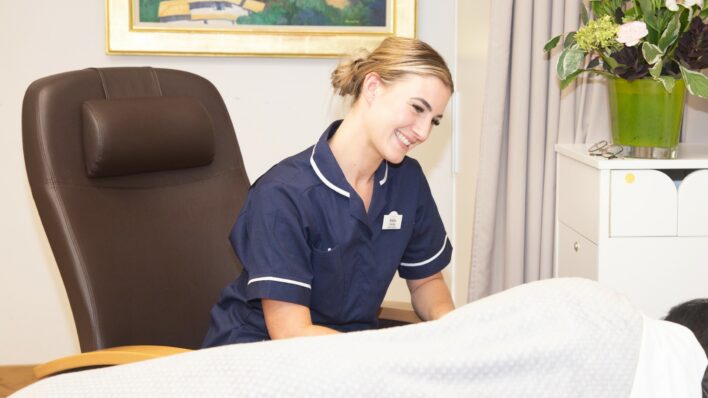Female nurse smiling at a bed