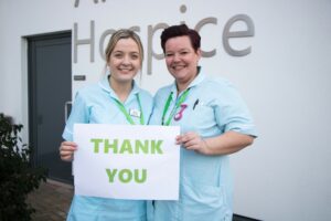 2 female nurses holding a thank you sign