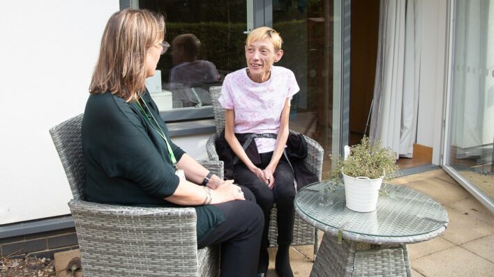 2 females outside sitting on chairs chatting