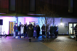 Choir outside of the hospice building. Blue and purple lights on the background.
