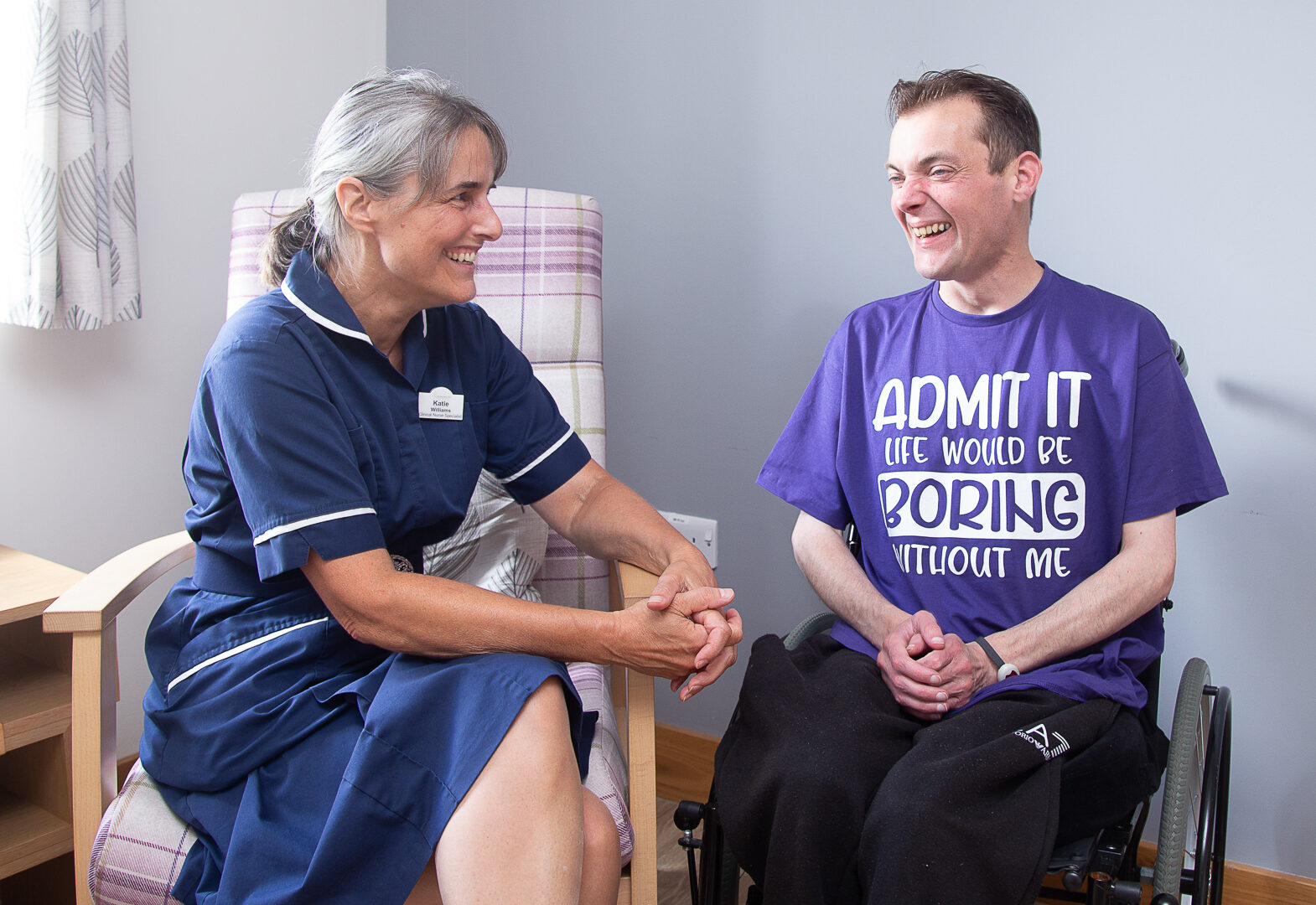 Female nurse talking to a male, sitting in a wheelchair
