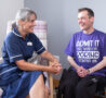 Female nurse talking to a male, sitting in a wheelchair