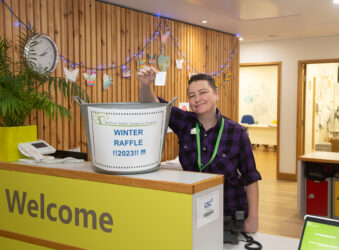 Female holding a raffle ticket in front of a bucket on reception area