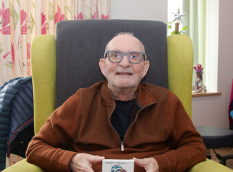 Male sitting in a chair, holding a small canvas