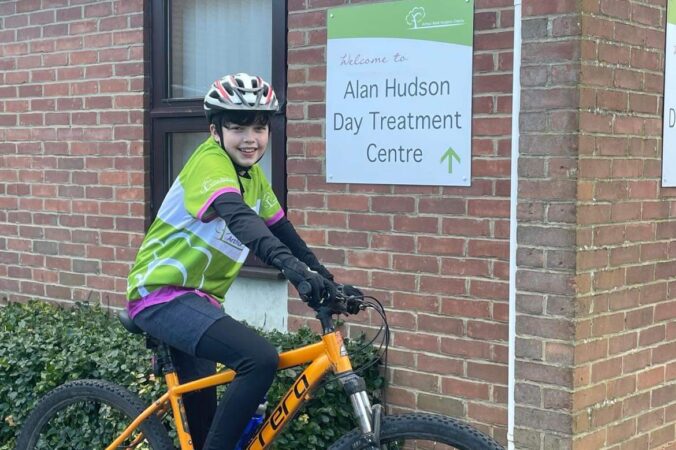 Young boy on a bike with green branded top
