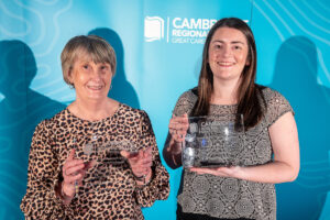 two females holding a glass award