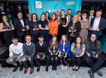 Group of males and females sitting and standing, holding glass awards
