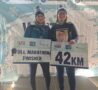 2 females wearing bobble hats holding a sign looking at the camera