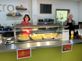 Two ladies standing in bistro. They are serving food.