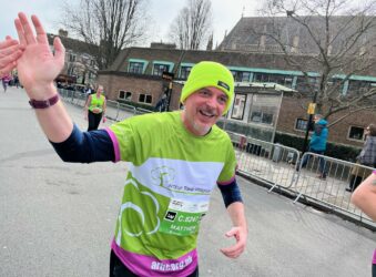 Male wearing green running gear waving