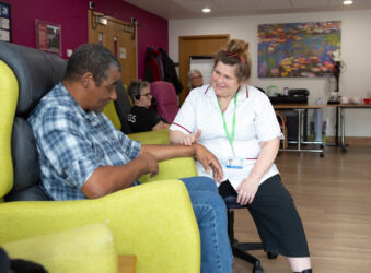 Male sitting on a chair talking to a female nurse