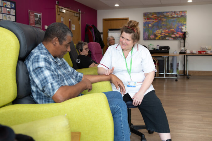 Male sitting on a chair talking to a female nurse