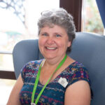 Female sitting on an arm chair, smiling at the camera