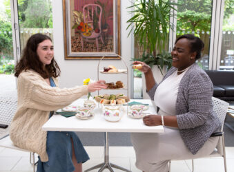 2 females sitting at a table with afternoon tea