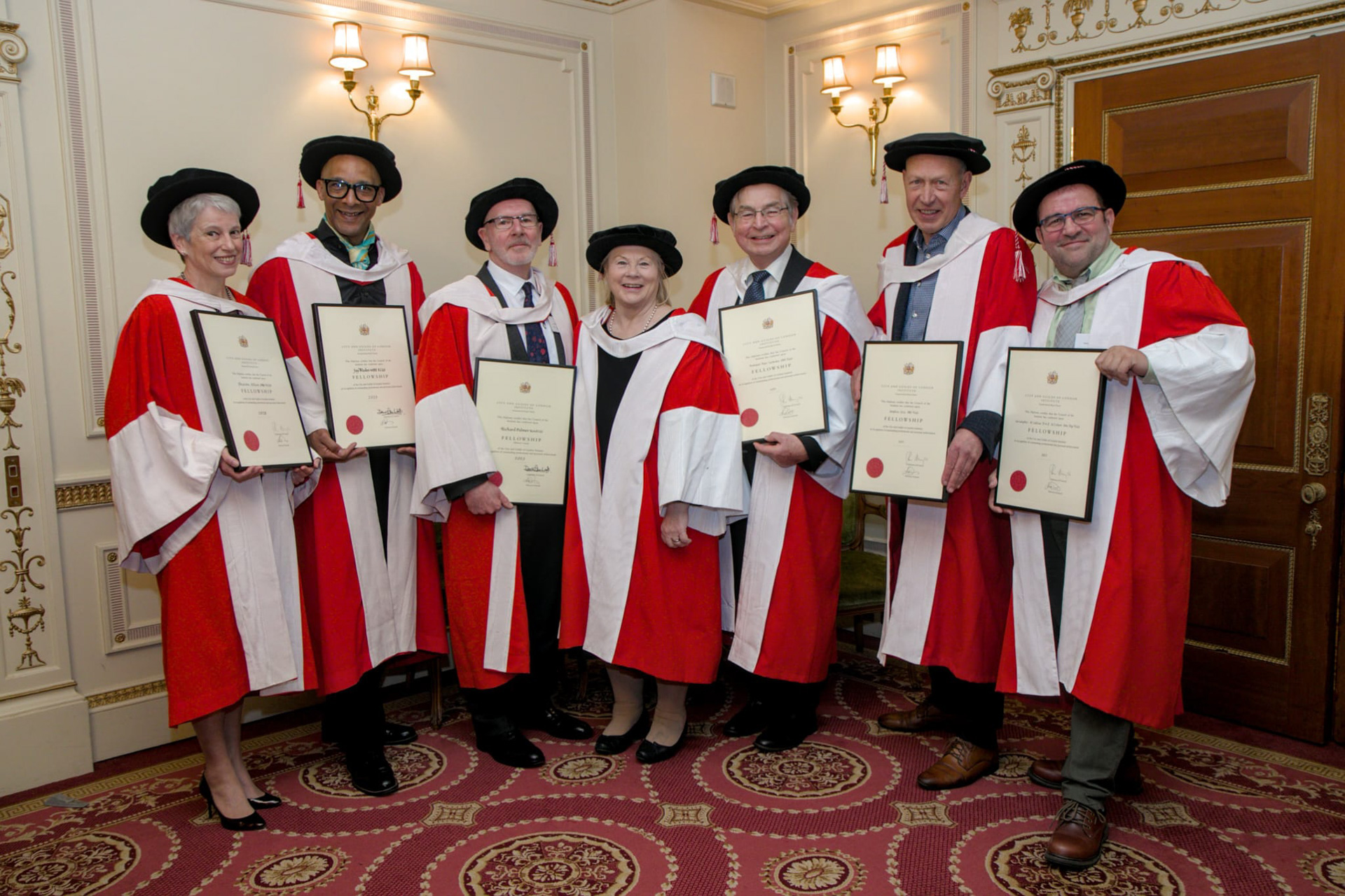 Males and females wearing red and white gowns holding certificates