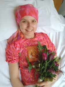 Female in bed wearing a pink dress and headscarf