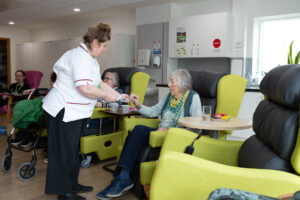 Female sitting in a chair and nurse offering a sweet 