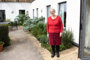 Female wearing red outside a building and garden