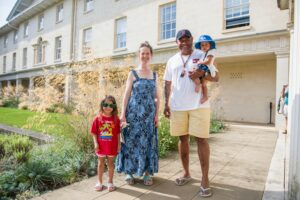 Male and female and 2 children standing near a building looking at the camera 