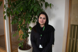 Female wearing black, standing near a plant