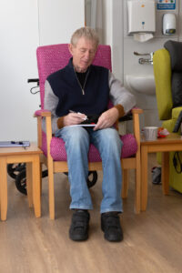 Male sitting in a chair writing 