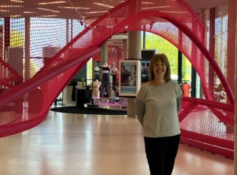 Female standing in front of a red structure inside a factory