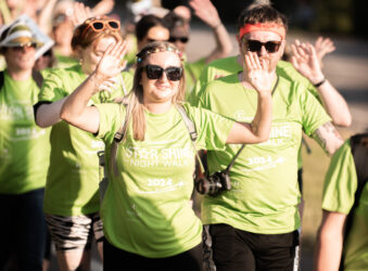 Male and females wearing green t-shirts walking outside