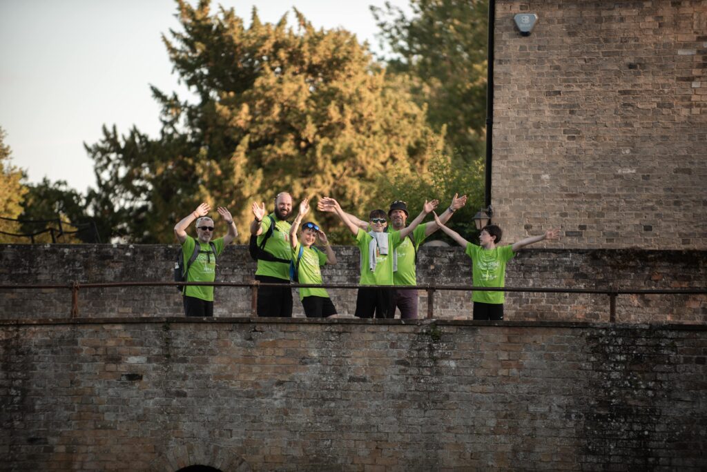 Group of men and boys on a bridge, wearing green tshirts and waving their arms in the air. 