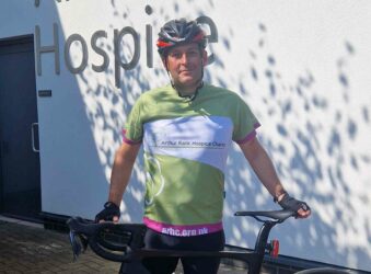 Image of man wearing green cycling tshirt and helmet posing with bike