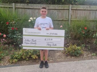 10 year old boy holding giant cheque in Garden