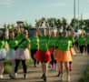 Males and females wearing colorful tutus walking and arms in the air