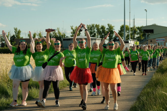 Males and females dressed in green outside cheering