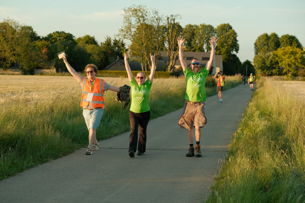 3 people walking with arms in the air